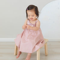 Girl wearing the 'Bird of Paradise' dress, showcasing the full skirt and sitting on a chair