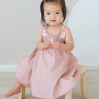 Girl wearing the 'Bird of Paradise' dress, showcasing the full skirt and sitting on a chair