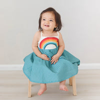 Dress with rainbow bodice and teal full twirly skirt shown on a model looking happy