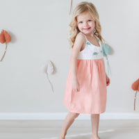 Girl looking cute and confident wearing dress that has turtle print on the top and a peachy slightly patterned fabric for the bottom