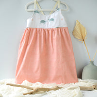 dress with turtle print design and peachy coordinating skirt shown hanging off a hanger