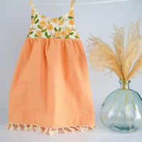 Dress hanging, showing puakenikeni floral design with fringe trim by bitty bambu