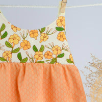 Close up of dress hanging, showing puakenikeni floral design with fringe trim by bitty bambu