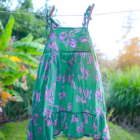 Handmade girls dress in Green Bougainvillea print with adjustable tie shoulder straps and ruffled hem, made out of 100% cotton