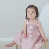 Video of a firl sitting on a chair wearing handmade bird of paradise dress by bitty bambu