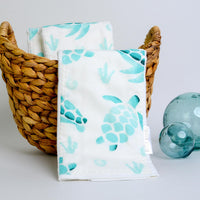 Towels with turtle pattern in a basket on a light background