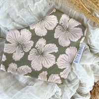A green bandana-style baby bib with a floral pattern laid out flat on a neutral surface.