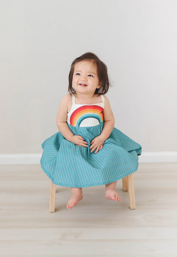 Dress with rainbow bodice and teal full twirly skirt shown on a model looking happy