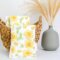 Floral-patterned towels in a wicker basket with a vase on a white background