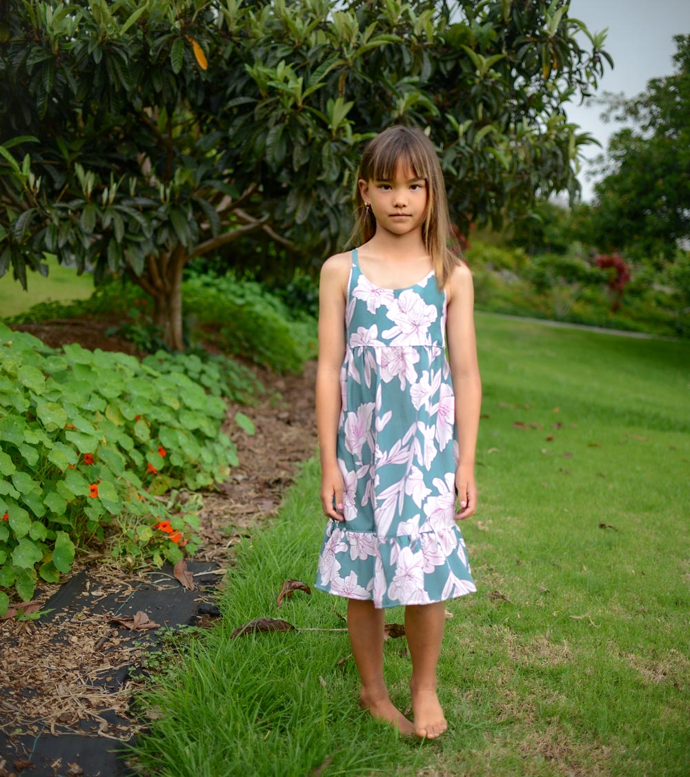 Girl wearing the 'Jade Pua' dress, showcasing the adjustable straps and ruffled hem.
