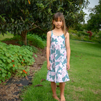 Girl wearing the 'Jade Pua' dress, showcasing the adjustable straps and ruffled hem.
