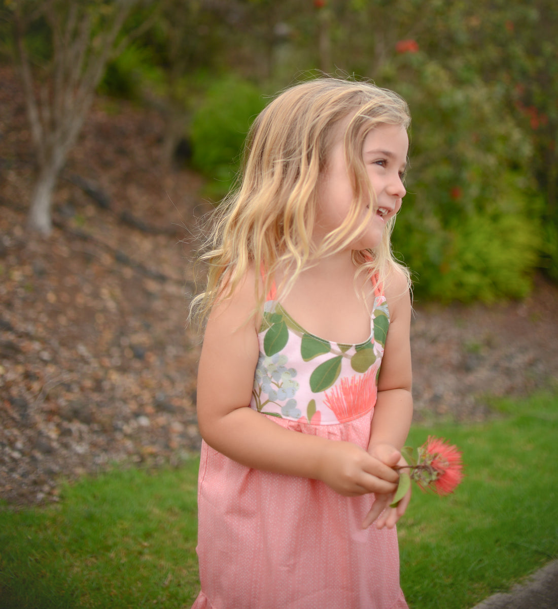 Girl wearing the Ohia Flower dress, displaying the vibrant native Hawaiian flower print and comfortable fit
