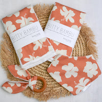 Bitty Bambu baby bibs with floral pattern on a woven mat
