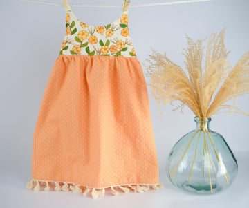 Dress hanging, showing puakenikeni floral design with fringe trim by bitty bambu