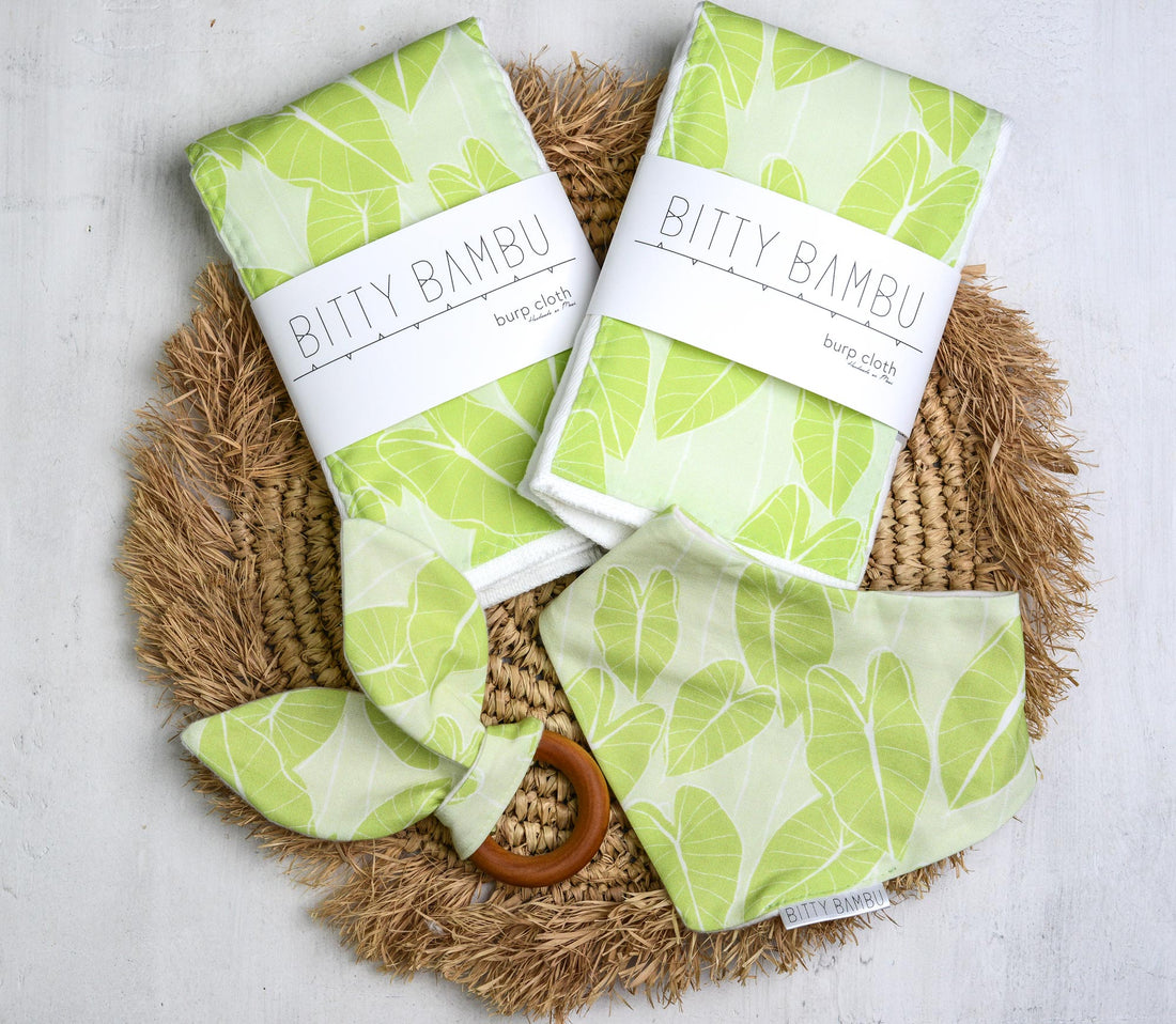 Two packages of Bitty Bambu baby cloths with green leaf pattern on a woven mat.