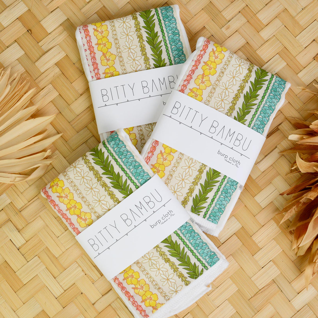 Bitty Bambu products on a woven surface with decorative leaves.
